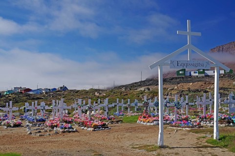Wooden crosses in front of graves decorated with colourful artificial flowers