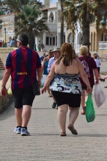 Overweight couple with plastic bags on beach promenade