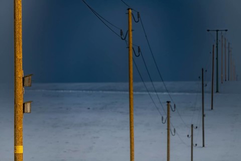 Electricity pylons in winter landscape against dramatic sky