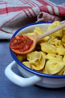 Pasta in pot and cooking spoon with tomato sauce