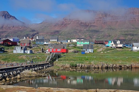 Simple bridge leading to houses reflected in a body of water