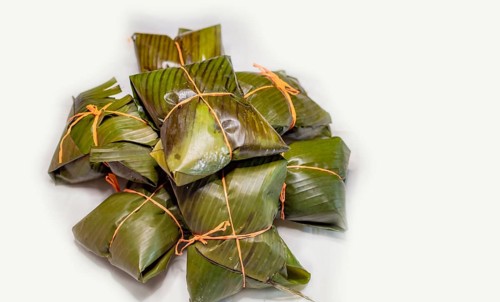 Close up of nacatamales with banana leaves on white background