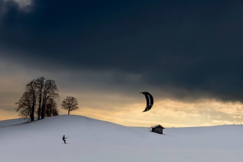 Kite surfers in winter landscape in front of dramatic sky