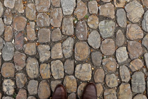 Brown shoe tips on brown stone pavement