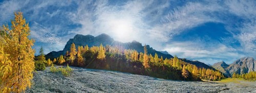 Glowing autumnal mountain forest below the Lamsenjoch massif with bizarre cloudy sky