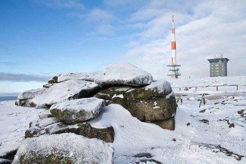 Rock with transmission mast and Brocken hostel on the wintery snow-covered Brocken