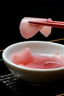 Sliced pickled ginger on chopsticks and in bowl