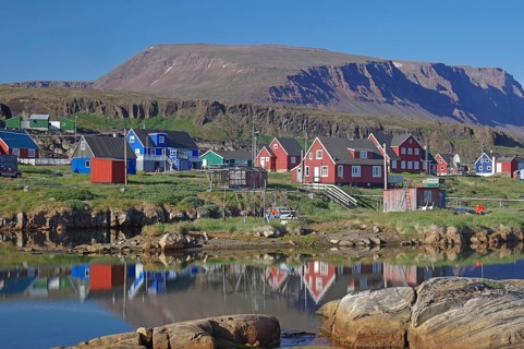 Wooden houses reflected in a body of water on a calm summer evening