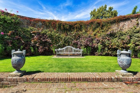Garden bench with two amphorae in a cottage garden