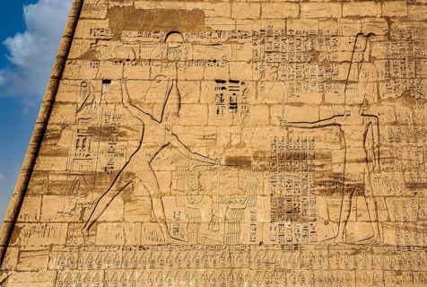 1st pylon in the funerary temple decorated with oversized relief depictions showing the pharaoh in typical displays of power slaying enemies in front of a deity