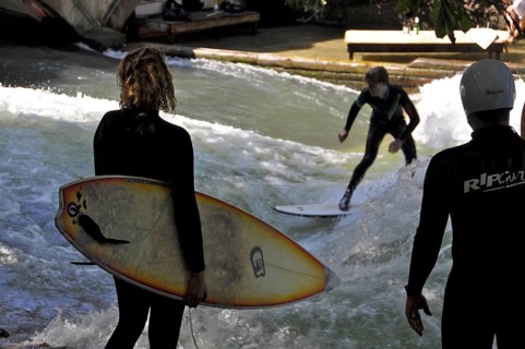 Sufers watch surfers riding the wave at the Eisbach