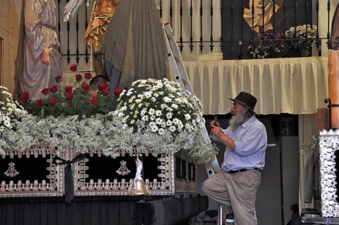 Old man with hat decorates altar in church for Easter procession