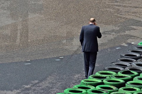 Man with mobile phone to ear in front of stacked car tyres at racecourse