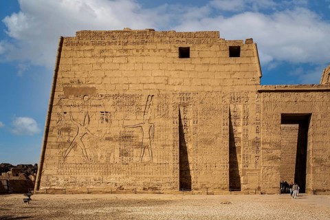 1st pylon in the funerary temple decorated with oversized relief depictions showing the pharaoh in typical displays of power slaying enemies in front of a deity