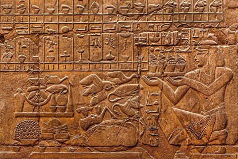 The kneeling king in front of a row of offerings