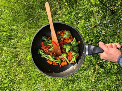 Hand holding pan with fried vegetables