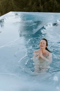 Woman folds her hands while ice bathing in the pool