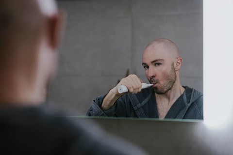 Man brushing his teeth in front of the bathroom mirror