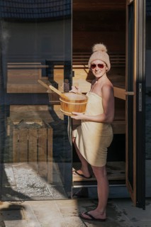 Woman with infusion tub in front of the sauna