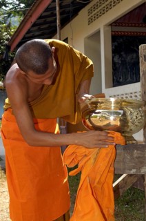 Buddhist monk cleans golden offering bowl in Buddhist monastery