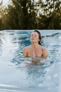 Woman folds her hands while ice bathing in the pool