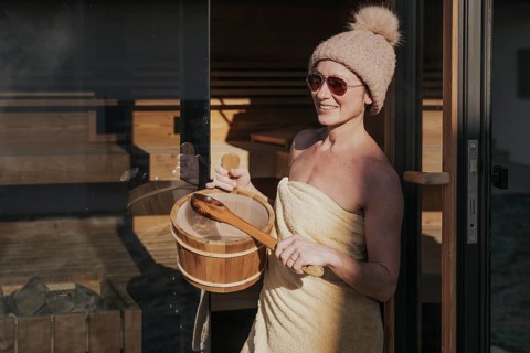 Woman with infusion tub in front of the sauna