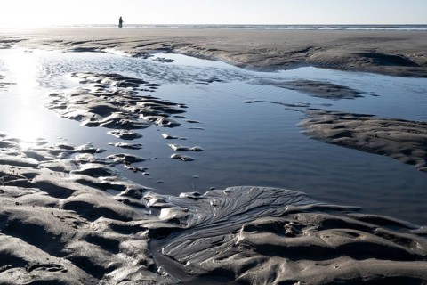 Walkers on the beach at low tide with tide pools