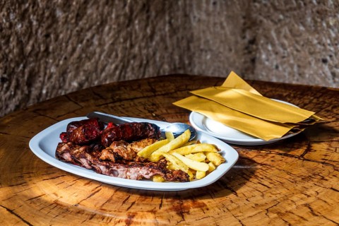 Mixed meat barbecued and served with french fries in restaurant in the cave
