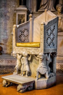 Bishop's chair resting on supporting figures with faces distorted by pain