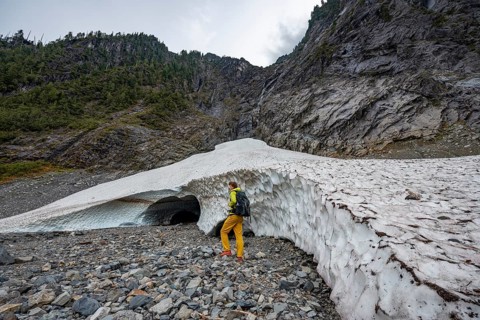 Hikers at the entrance of an ice cave of a glacier
