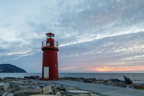 Sunrise with lighthouse at the harbour pier in Porto Maurizio