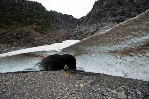 Hikers at the entrance of an ice cave of a glacier