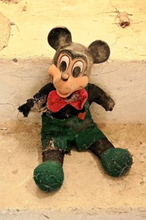 Demolished rag doll of a Mickey Mouse leaning against the wall