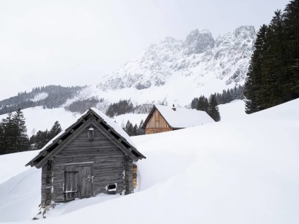 Winter landscape with alpine huts in front of snow-covered Bosruck massif