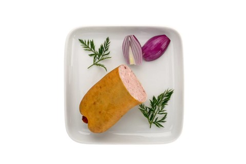 Coarse liver sausage in one piece on a plate with onions