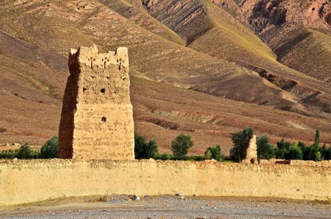 Clay fortress with tower in front of bare mountains