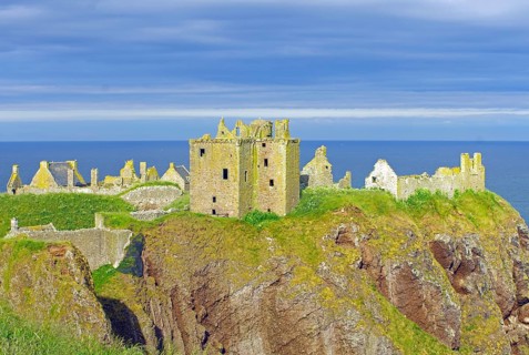 The ruins of a castle lie on a cliff in the evening sun