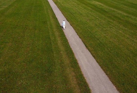 Frail woman walking with a Rolator along a narrow path