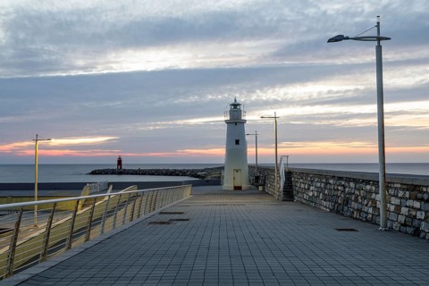 Sunrise with lighthouse at the harbour pier in Porto Maurizio