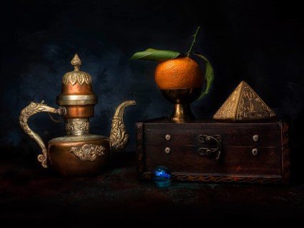 Still life with mandarin and gilded pyramid on wooden box