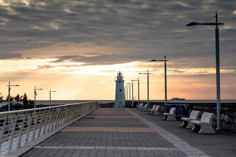 Sunrise with lighthouse at the harbour pier in Porto Maurizio