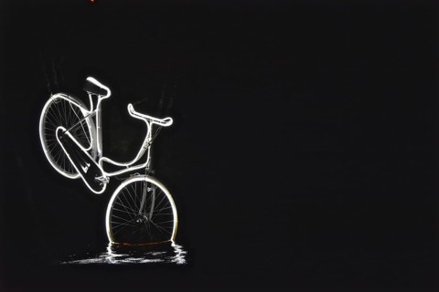 Neon-lit bicycle dives into the water of a canal