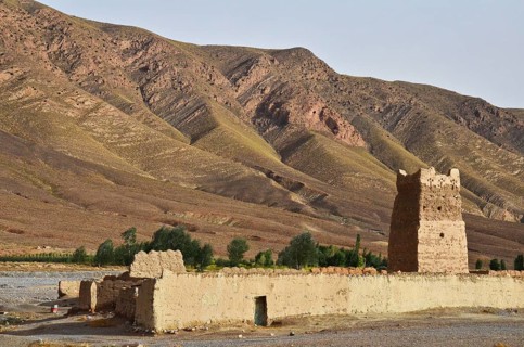 Clay fortress with tower in front of bare mountains
