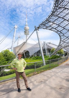 Friendly smiling man at the Olympic tower with Olympic tent roof