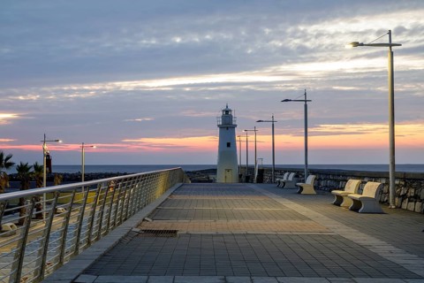 Sunrise with lighthouse at the harbour pier in Porto Maurizio