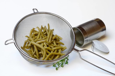 Green beans and savory in sieve and tin