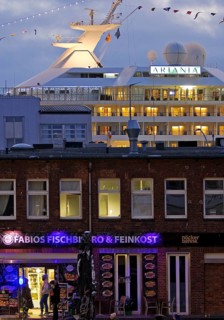 Fish market shops and cruise ship Artania at Hamburg Cruise Center Altona in the evening