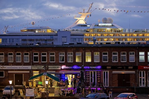 Fish market shops and cruise ship Artania at Hamburg Cruise Center Altona in the evening