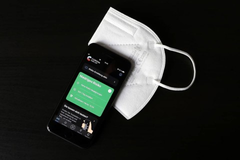 FFP2 mask and iPhone with low-risk Corona warning app