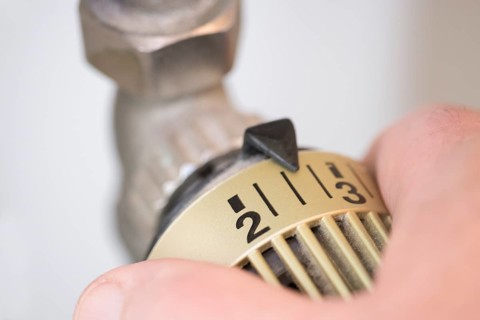 Hand on the heating thermostat